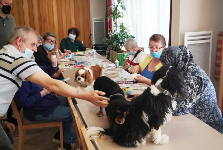 photo de l'atelier avec nos résidents et sur la table d'activités, les 3 cavaliers king charles