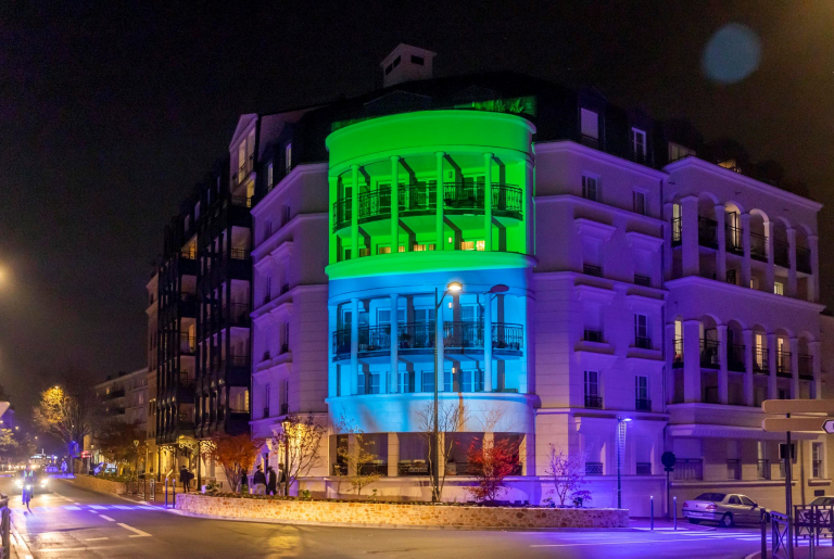 Villa Impériale, photo de la façade de nuit éclairée aux couleurs d'ICADE (vert, bleu et violet) - photo par l'agence IP3 Press